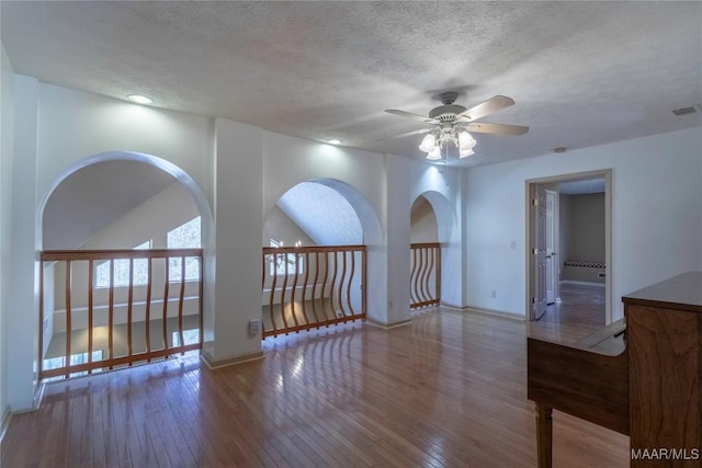 spare room featuring hardwood / wood-style flooring, ceiling fan, baseboards, and a textured ceiling