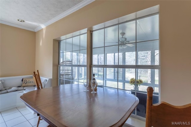 tiled dining space featuring a healthy amount of sunlight, ceiling fan, ornamental molding, and a textured ceiling