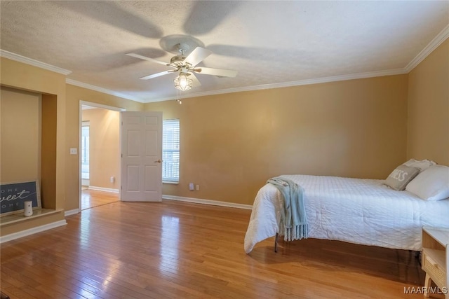 bedroom with a textured ceiling, ornamental molding, wood-type flooring, and baseboards