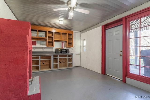 interior space with concrete flooring, plenty of natural light, ceiling fan, and open shelves