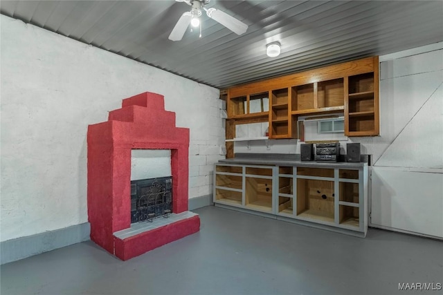 interior space with concrete flooring, a brick fireplace, and ceiling fan