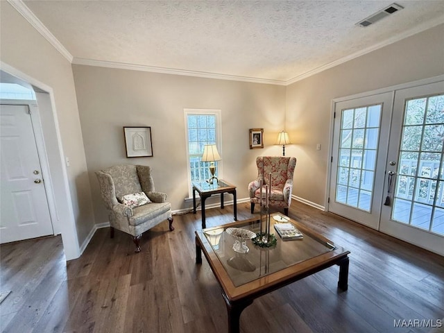 living area featuring a textured ceiling, wood finished floors, visible vents, and crown molding