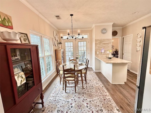 dining space with dark wood-style floors, a textured ceiling, visible vents, and crown molding