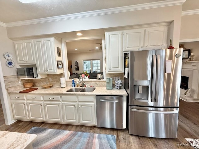 kitchen featuring appliances with stainless steel finishes, crown molding, a sink, and wood finished floors