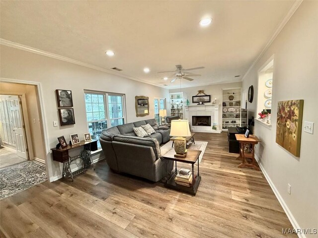 living area with crown molding, a fireplace, wood finished floors, and baseboards