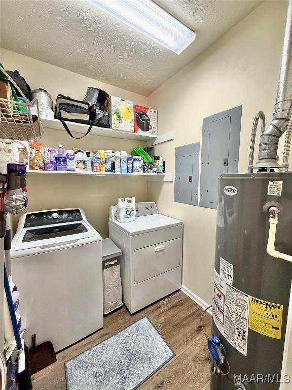 clothes washing area with laundry area, electric panel, washer and clothes dryer, and gas water heater