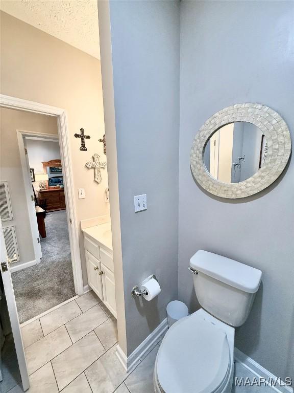 bathroom featuring toilet, baseboards, a textured ceiling, and vanity