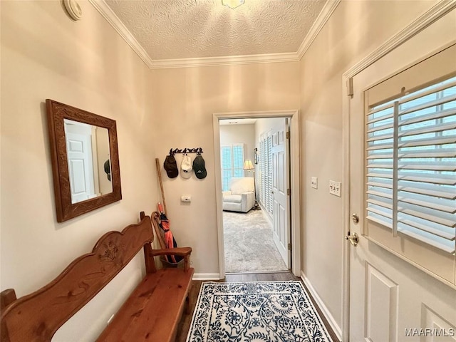 doorway to outside featuring a textured ceiling, ornamental molding, and baseboards