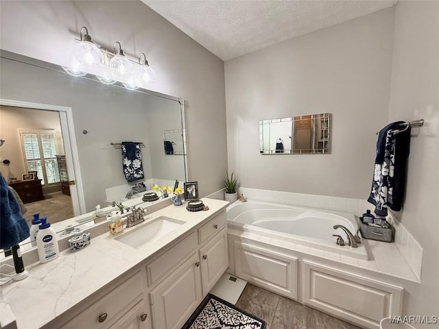 full bath with a garden tub, a textured ceiling, and vanity