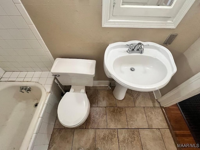 bathroom with toilet, a sink, a bathtub, and baseboards