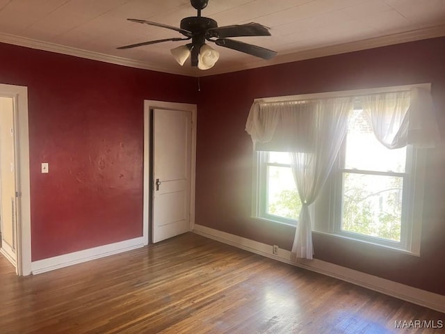 spare room featuring ceiling fan, crown molding, baseboards, and wood finished floors