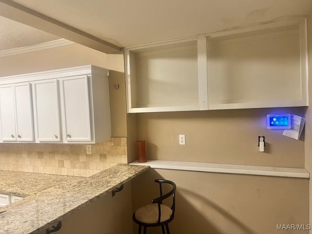 kitchen with white cabinetry, decorative backsplash, open shelves, built in desk, and crown molding