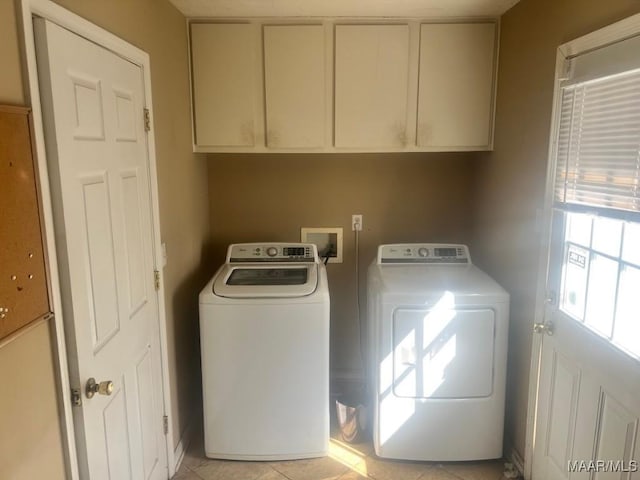 clothes washing area featuring cabinet space, washer and dryer, and light tile patterned flooring