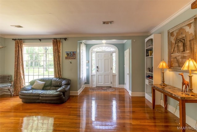 entryway featuring baseboards, crown molding, visible vents, and wood finished floors