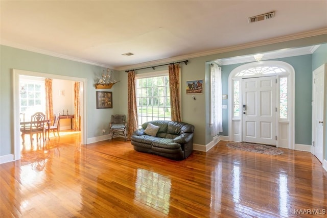 foyer with light wood-style flooring, visible vents, and ornamental molding