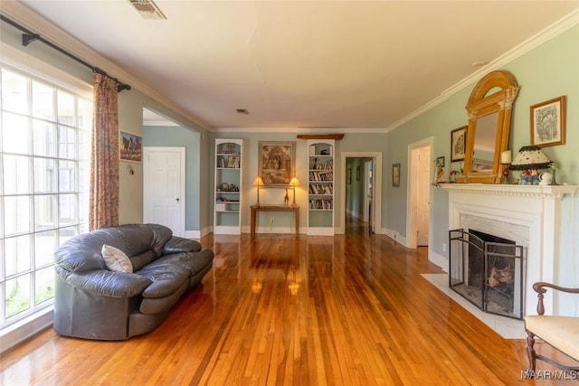 living room featuring a fireplace with flush hearth, visible vents, a wealth of natural light, and wood finished floors