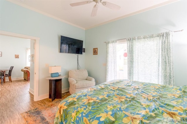 bedroom with light wood-style floors, crown molding, baseboards, and ceiling fan