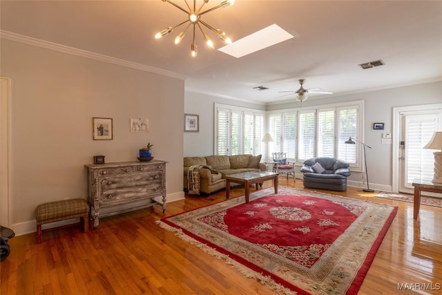 living room featuring a skylight, crown molding, visible vents, wood finished floors, and baseboards