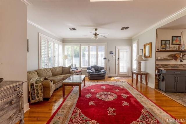 living area with ornamental molding, visible vents, and light wood-style floors