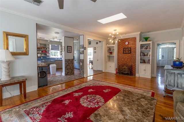 entrance foyer featuring a chandelier, visible vents, crown molding, and wood finished floors