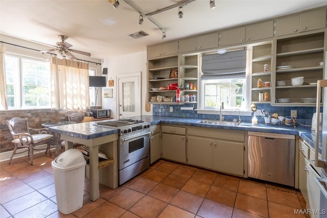 kitchen featuring tasteful backsplash, appliances with stainless steel finishes, open shelves, and a sink