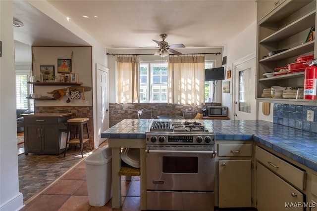 kitchen featuring open shelves, stainless steel range, a peninsula, and a wealth of natural light