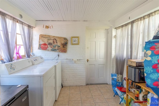 washroom with light tile patterned floors, washing machine and dryer, brick wall, laundry area, and wood ceiling