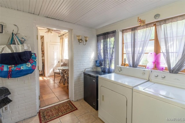 laundry room with laundry area, light tile patterned flooring, brick wall, and separate washer and dryer