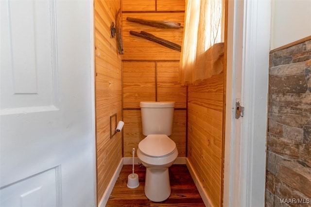 bathroom featuring wooden walls, toilet, and wood finished floors