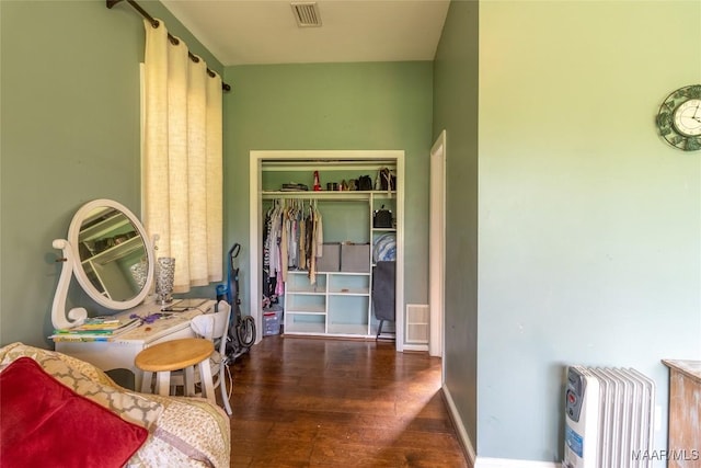 bedroom featuring a barn door, a closet, visible vents, and wood finished floors