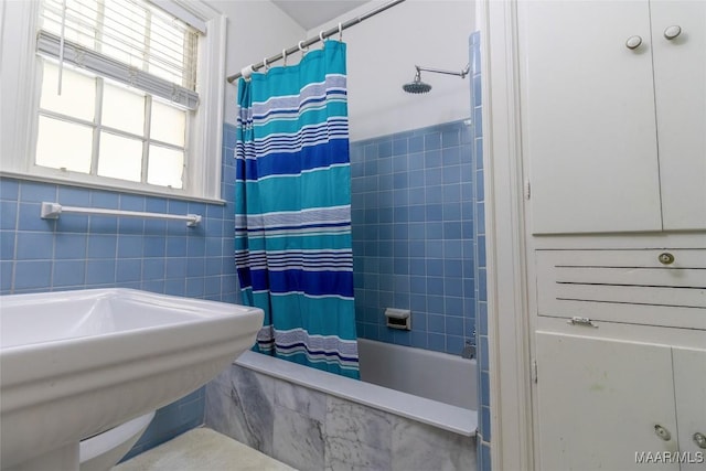 bathroom featuring tiled shower / bath, a sink, and tile walls