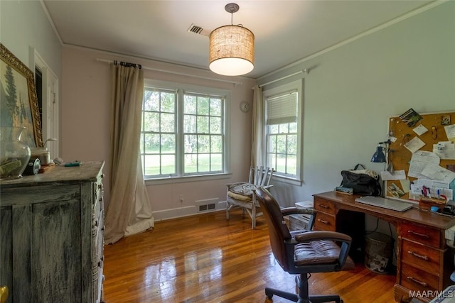 home office with baseboards, crown molding, visible vents, and wood finished floors