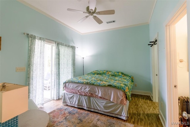 bedroom with baseboards, visible vents, a ceiling fan, ornamental molding, and wood finished floors