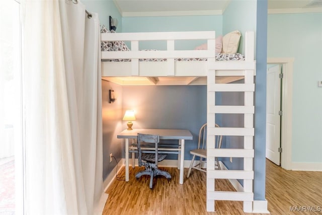 bedroom with baseboards, wood finished floors, and crown molding