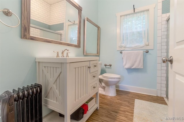 full bath with baseboards, toilet, radiator heating unit, wood finished floors, and vanity