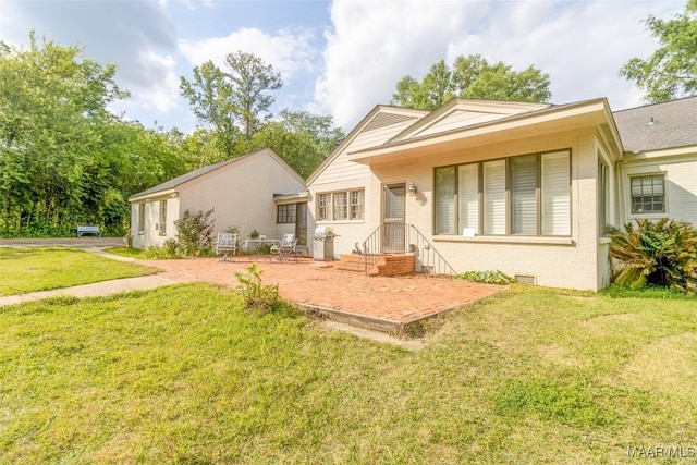 rear view of house featuring a patio area, brick siding, and a lawn