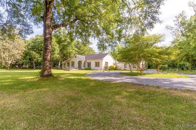 view of front of home featuring a front lawn and gravel driveway