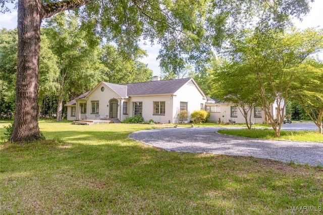 view of front of property featuring driveway, a front lawn, and a chimney