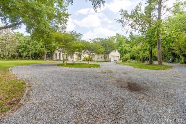 view of front of home featuring gravel driveway and a front lawn