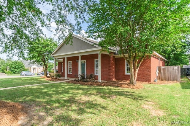 view of front of home with covered porch, brick siding, fence, and a front lawn