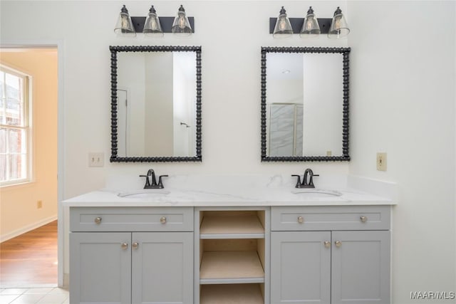 full bathroom with double vanity, baseboards, a sink, and wood finished floors