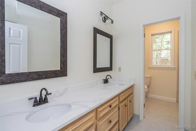 bathroom with tile patterned flooring, a sink, toilet, and double vanity