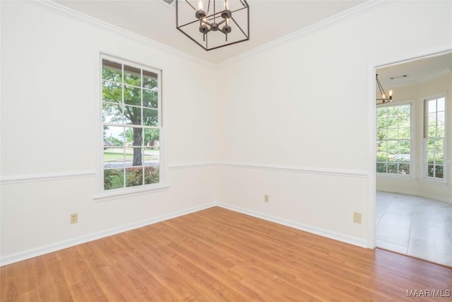 empty room featuring a chandelier, baseboards, light wood-style flooring, and crown molding