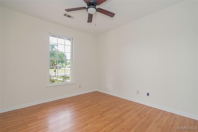 spare room featuring baseboards, ceiling fan, visible vents, and light wood-style floors