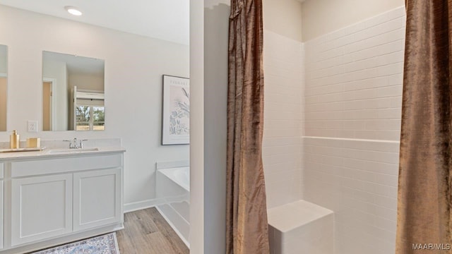 bathroom with a garden tub, wood finished floors, vanity, and baseboards