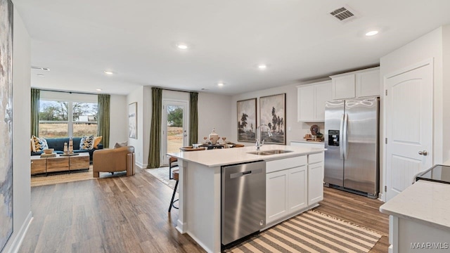 kitchen featuring stainless steel appliances, recessed lighting, light wood-style flooring, white cabinetry, and a sink