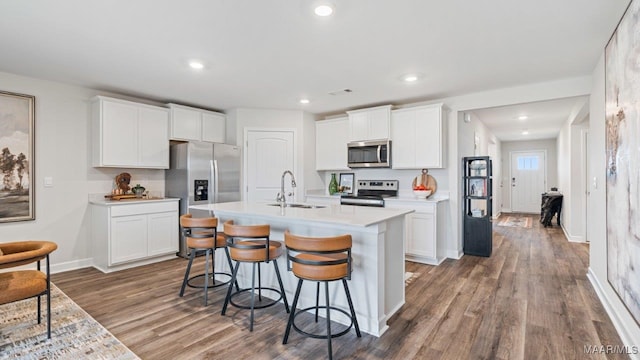 kitchen with white cabinets, dark wood-type flooring, stainless steel appliances, light countertops, and a sink