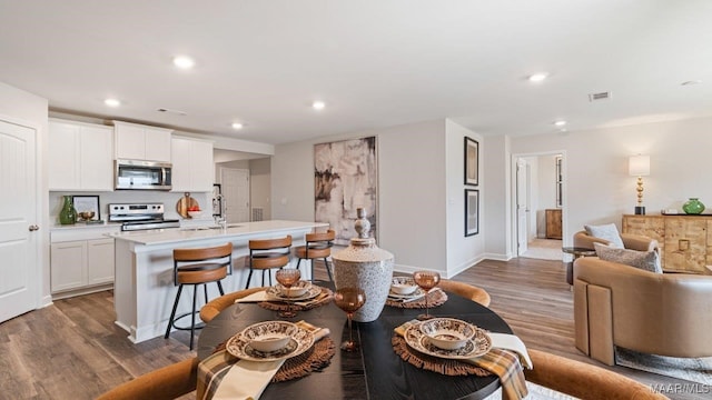 dining room with baseboards, wood finished floors, visible vents, and recessed lighting