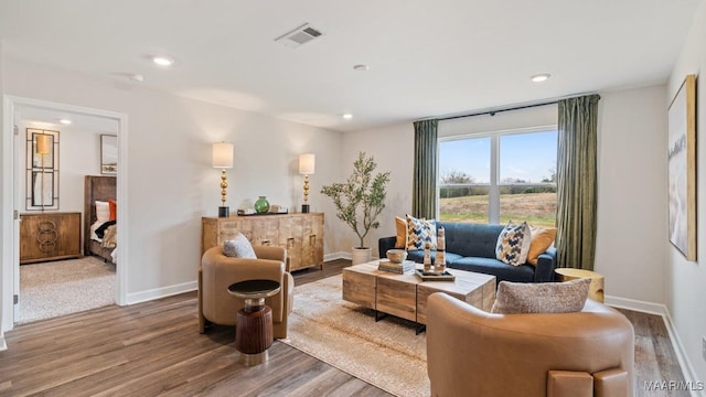 living room with recessed lighting, visible vents, baseboards, and wood finished floors