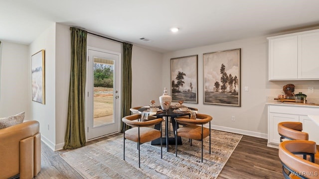 dining area with visible vents, baseboards, and wood finished floors